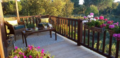 a wooden deck with a table and flowers on it at Ying Yang Monte da Lua in Comporta