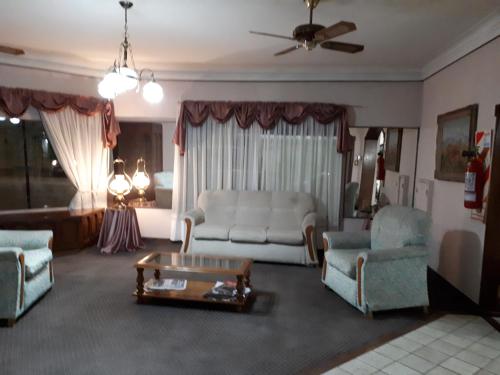 Una sala de estar con un sofá y sillas y una mesa. en Hotel Alcázar, en Villa María