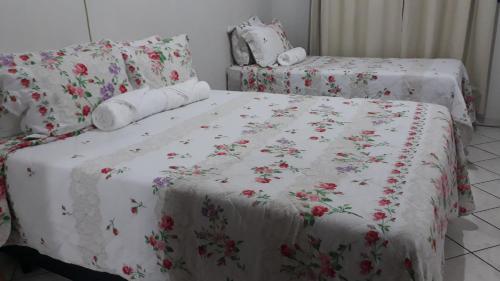 a bed with a white blanket with flowers on it at Home Sweet Home Flats in Brasilia