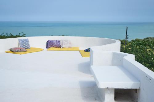 biała ławka z dwoma poduszkami i oceanem w obiekcie Casa Caracola w mieście Tubará