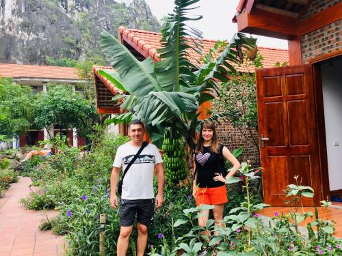 a man and a woman standing in front of a garden at Tam Coc Friendly Homestay in Ninh Binh