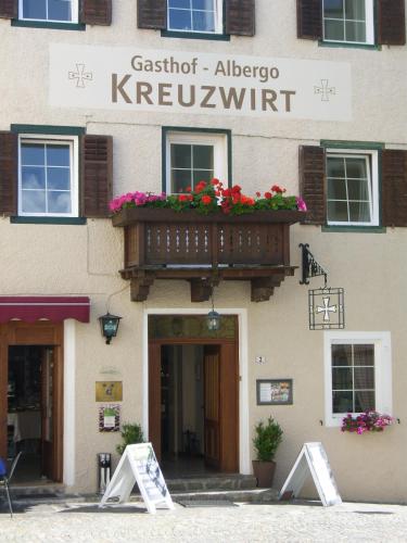a building with a balcony with flowers on it at Gasthof Albergo Kreuzwirt in Fiè