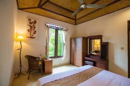 Pondok Permata Homestay في أوبود: غرفة نوم بسرير وتلفزيون ونافذة