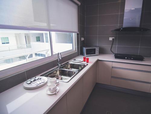 uma pequena cozinha com um lavatório e uma janela em Aman Hills Hotel em Kampong Timbunan