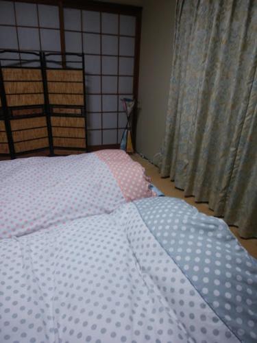 a bed with a polka dot comforter in a bedroom at Japanese Style Inn Dohzen Miwa in Niimi