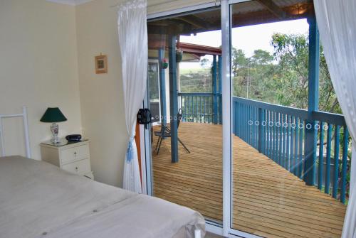 a bedroom with a bed and a balcony with a deck at Annie's Balquhidder Cottage in Victor Harbor