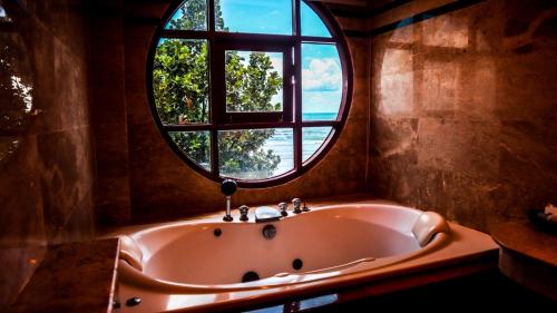 a bath tub in a room with a round window at Mac Resort Hotel in Ko Chang