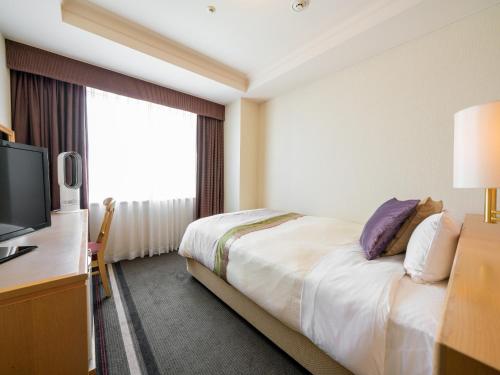 a hotel room with a bed and a television at Keio Plaza Hotel Hachioji in Hachioji