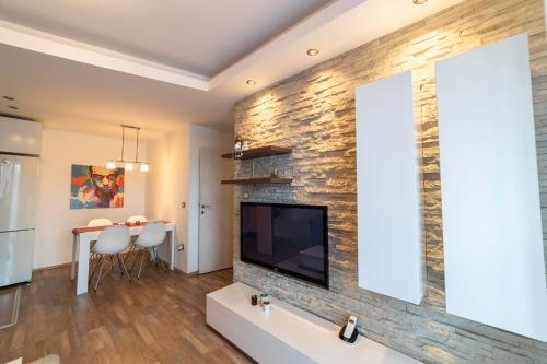 VF Kragujevac Apartments في كراغويفاتش: غرفة معيشة مع جدار حجري مع تلفزيون بشاشة مسطحة