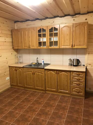 eine Küche mit Holzschränken und einem Waschbecken in der Unterkunft Mini-Hotel "Nord" in Chynadiyovo
