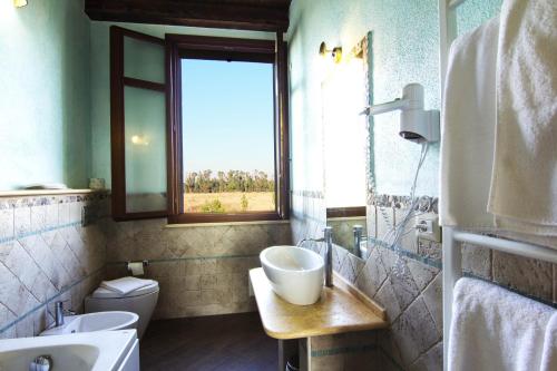 baño con lavabo, espejo y ventana en SU PASSU Country House, en Fertilia
