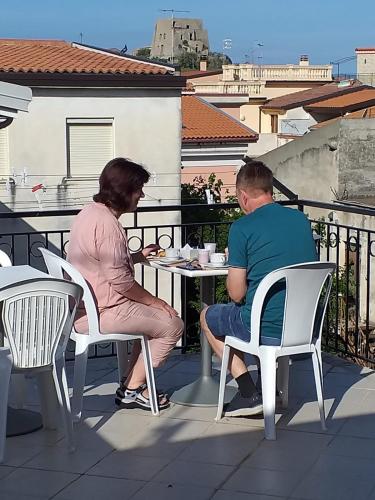 a man and woman sitting at a table on a balcony at B&B Dimora del centro in Scalea