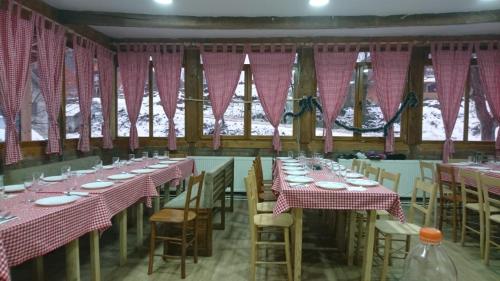 a dining room with tables and chairs and pink curtains at Domacinstvo Kod Gere in Crni Vrh