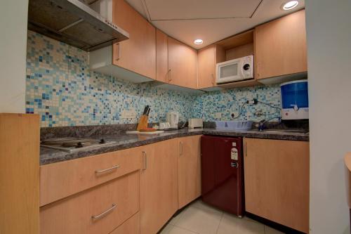 a kitchen with wooden cabinets and a red dishwasher at Tristar Serviced Apartments in Bengaluru
