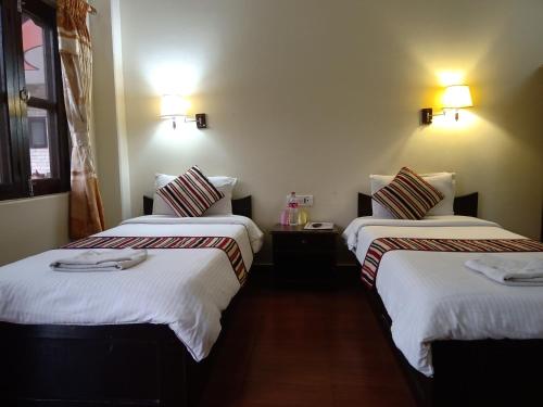 a hotel room with two beds with white sheets at Butterfly Lodge in Pokhara