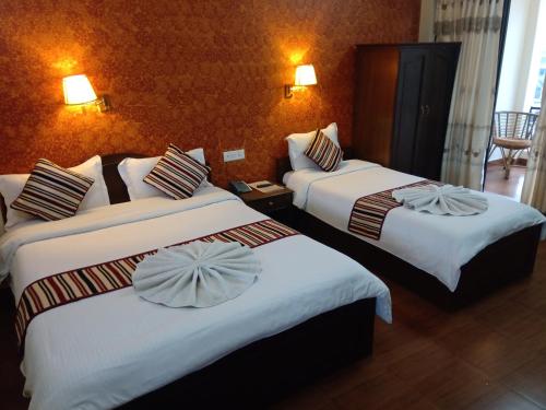 a hotel room with two beds with white sheets at Butterfly Lodge in Pokhara