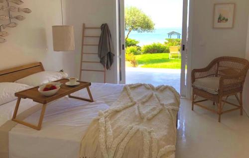 a bedroom with a bed with a table and a chair at Aqua Seafront Glyfada Corfu Beach House With Garden in Glyfada