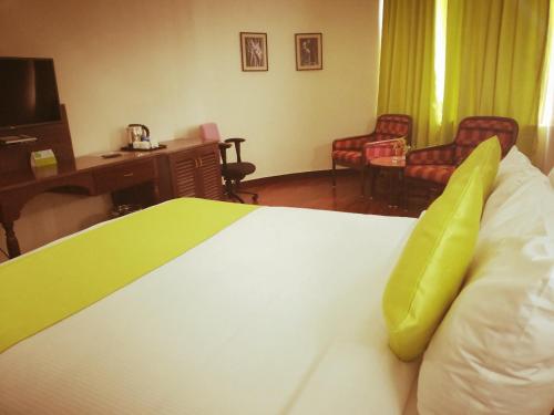 a hotel room with a bed with a green pillow at Presidency Kochi City Centre in Cochin