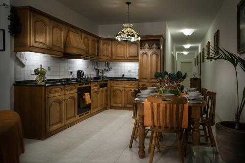 a kitchen with wooden cabinets and a table with chairs at Manor Court Luxury Apartment in St Paul's Bay