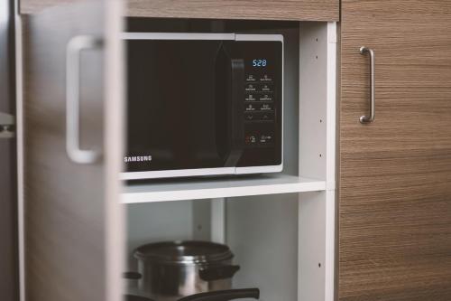 a microwave on a shelf in a kitchen at Jauki studija su dideliu balkonu Nidos centre in Nida
