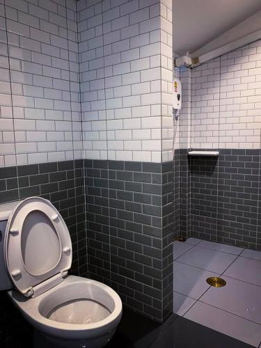 a bathroom with a toilet and a tiled wall at Coconut Grove Hotel Samui in Chaweng