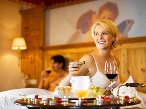 a woman sitting in a bed with a glass of wine at ... mein romantisches Hotel Toalstock in Fiss
