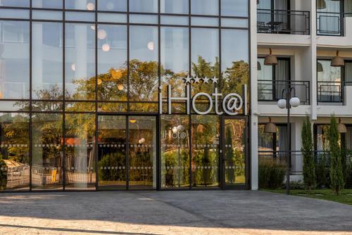 un grand bâtiment en verre avec un panneau. dans l'établissement iHotel Sunny Beach, à Sunny Beach