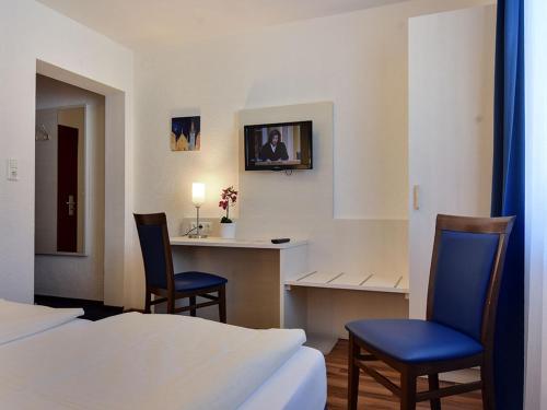 a hotel room with two beds and a desk and two chairs at Hotel Olympia in Munich