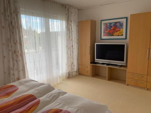 a bedroom with a bed and a tv and a window at Schöne Zimmer im Zentrum Leben in Offenburg