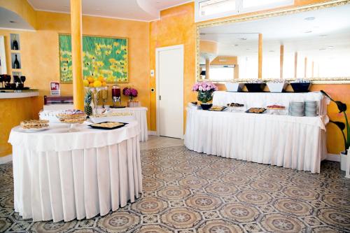 ein Restaurant mit weißen Tischen und Essen darauf in der Unterkunft Hotel Iva in Diano Marina