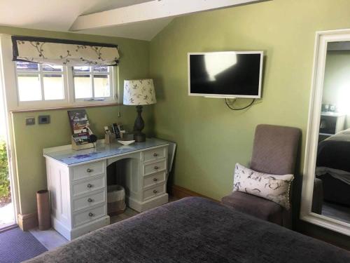a bedroom with a bed and a desk and a tv at The Black Horse at Ireland in Shefford