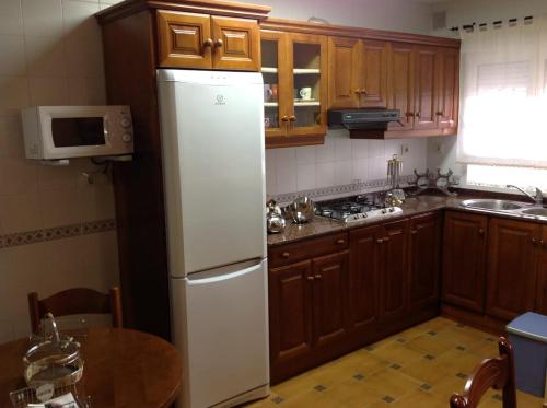 a kitchen with a white refrigerator and wooden cabinets at El Mirador de Biedes in Infiesto