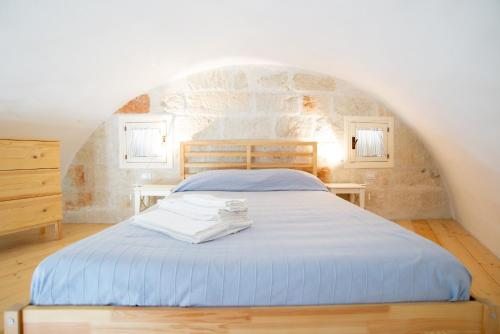 a bedroom with a blue bed with a stone wall at Casa Polignano in Polignano a Mare
