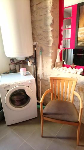 a laundry room with a washing machine and a chair at Gîtelabaronnaise avec piscine chauffée prés parc Asterix in Baron