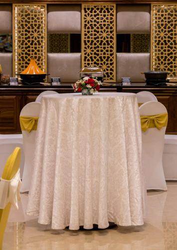 a white table with a vase of flowers on it at Regenta Central Cassia Zirakpur Chandigarh in Chandīgarh