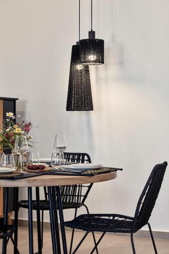 a dining room table with black chairs and aendant light at Callia Retreat Suites - Adults Only in Fira