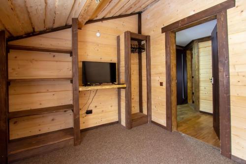 a room with wooden walls and a tv in a cabin at Guest House Plai in Yaremche