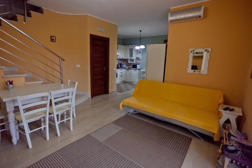 a living room with a yellow couch and a table at Casa solare in Bivona