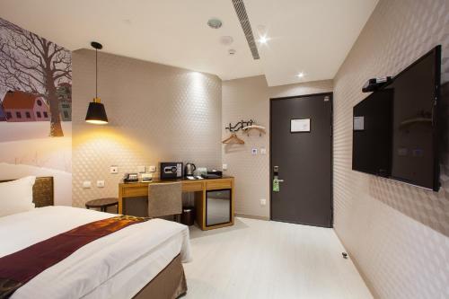 a bedroom with a bed and a desk and a tv at Stay Hotel - Taichung Zhongqing in Taichung