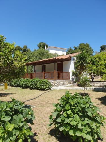 una casa con porche y algunos arbustos en Panos Villas en Koukounaries