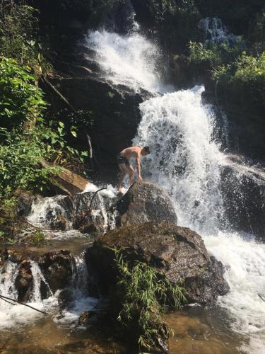 a man standing on a rock in a waterfall at Nok Chan Mee Na in Chom Thong