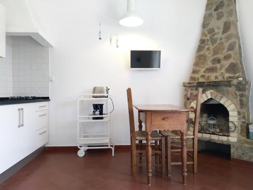 a kitchen with a table and a fireplace at Casa dos Pinheiros in Praia da Arrifana