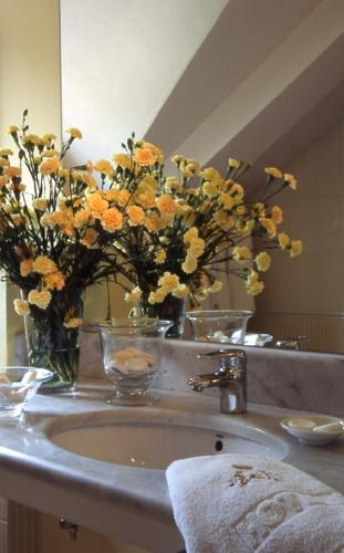 a bathroom sink with a vase of flowers on it at Hotel Maltański in Kraków