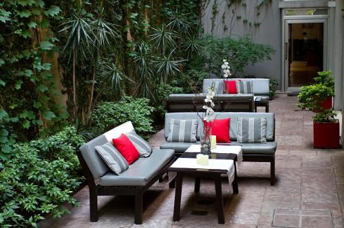 a patio with couches and a table with red pillows at Ribera Sur Hotel in Buenos Aires
