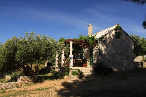 una pequeña casa de piedra con una valla y árboles en Holiday home Ivan Bol, en Bol