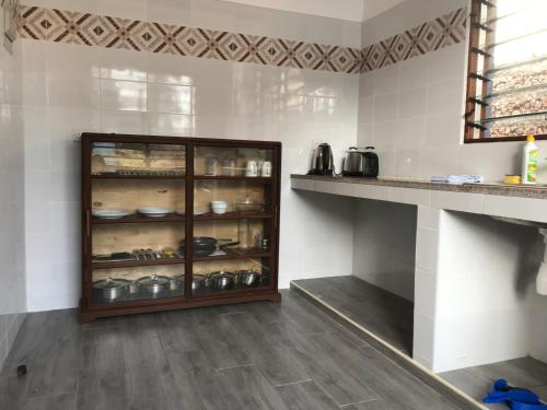 a kitchen with a glass cabinet with pots and pans at Lions Home in Diani Beach