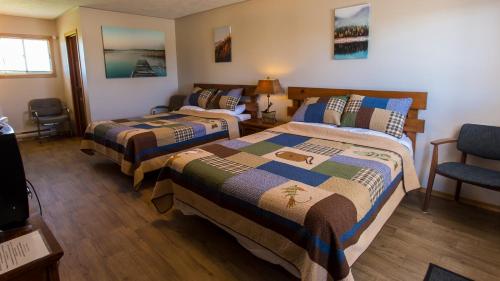 ein Hotelzimmer mit zwei Betten und einem Stuhl in der Unterkunft Bear Tracks Inn in Lions Head