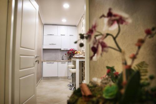 a kitchen with white cabinets and a table with flowers at B&B Pompei Olympus in Pompei