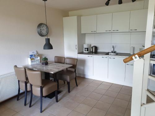 a kitchen with a table and chairs and a clock at De Groede in Oosterend