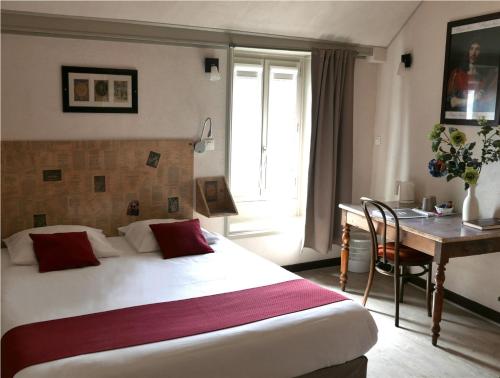 a hotel room with a bed and a desk at Hôtel Mille et une Feuilles in La Charité-sur-Loire